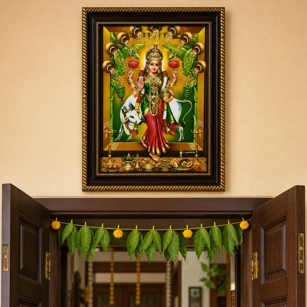 Griha Lakshmi photo frame hung above home entrance with mango leaf toran