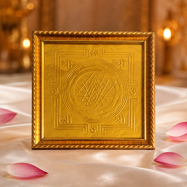 Gold Sri Chakra Yantra frame placed in front of temple altar with lotus flowers