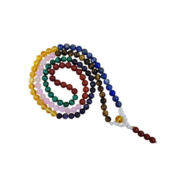 A 7 Chakra crystal mala necklace featuring multi-colored prayer beads arranged in a spiral on a white background.