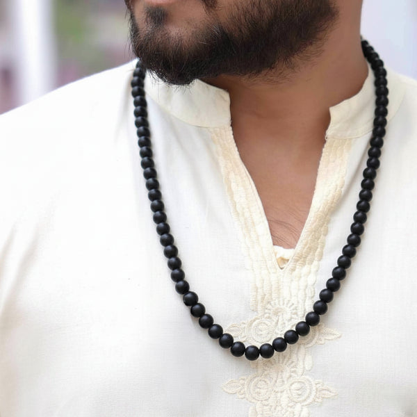 Authentic 8mm black Karungali bead necklace worn by a devotee, used for spiritual protection and prayer.

