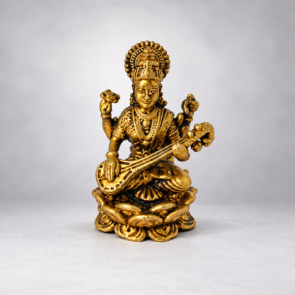 Small brass Saraswati idol seated on a lotus playing the veena