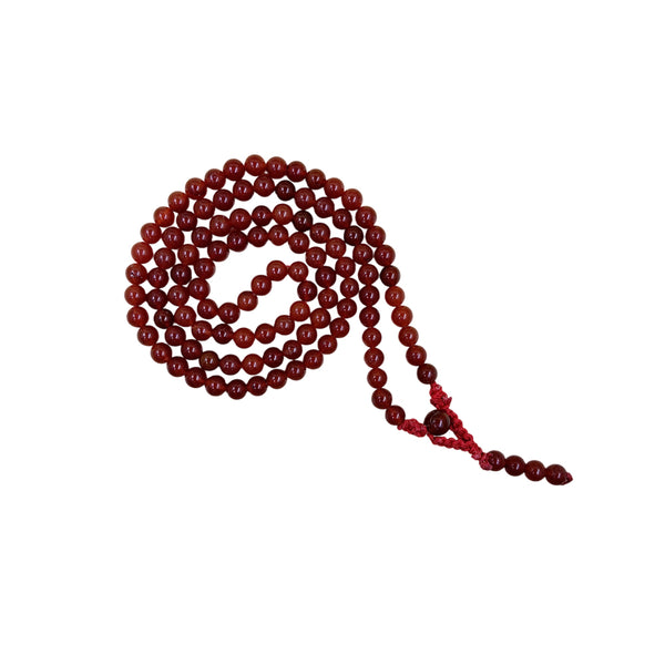 A traditional Red Carnelian crystal prayer mala coiled in a spiral on a white background, showcasing the uniform round reddish-orange beads and matching red cord.