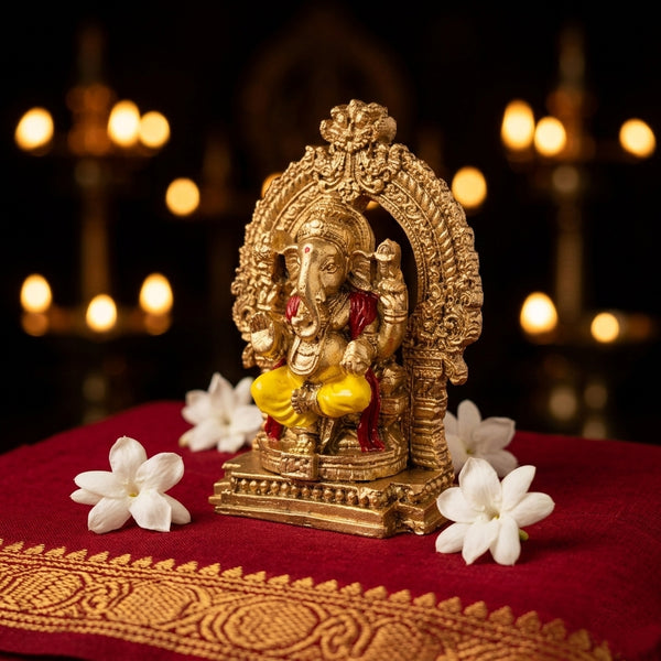 Side-angled view of the golden fiber Ganesha idol showing the hand-painted red and yellow detailing, perfect for a car dashboard or office desk.