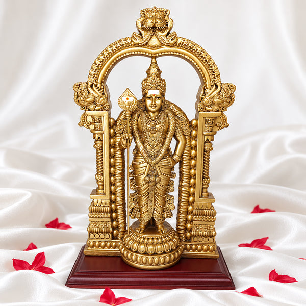 Front view of gold Murugan statue with temple arch on white silk with red petals