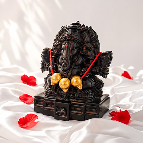 Trimukhi Ganpati statue on white satin with red flower petals