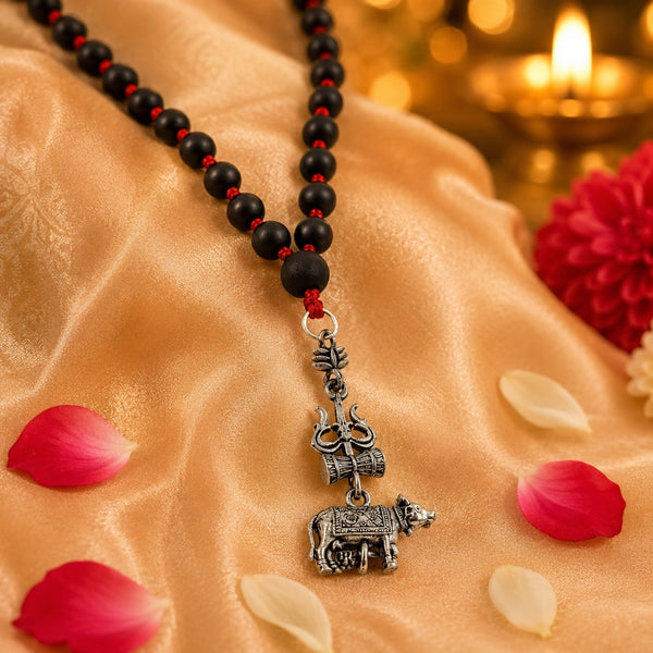 Hand-knotted 6mm original karungali kattai mala with a white metal Trishul and Nandhi pendant resting on golden silk.